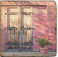 Load image into Gallery viewer, Cork back trivet with wooden door with metal bars on a textured lavender background.
